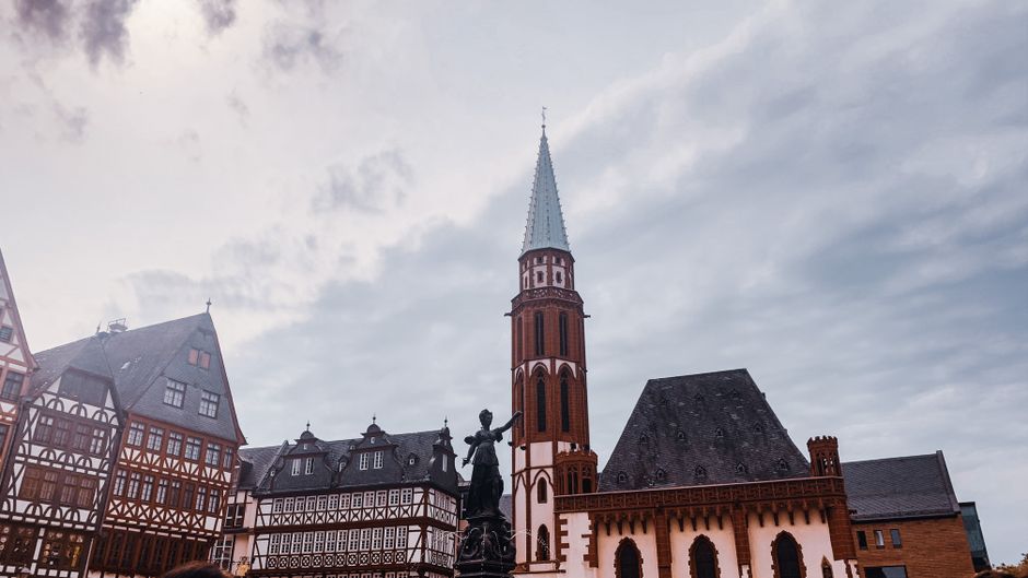 Stunning view of gothic architecture with a prominent tower in a city square under a cloudy sky.